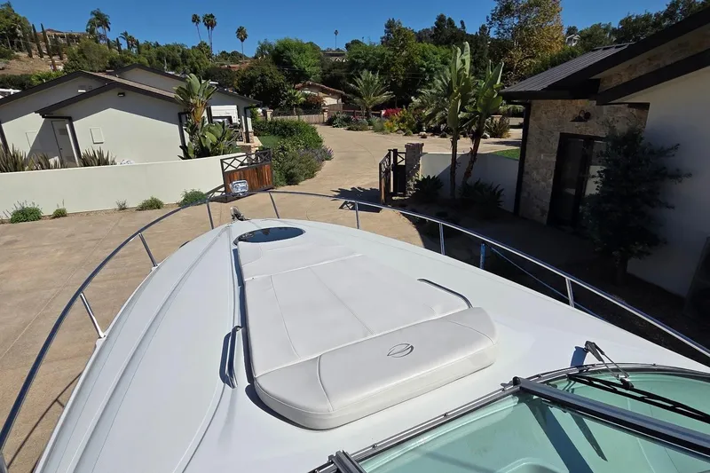 Slide: The Image of 2013 Crownline 325 SCR boat docked in a residential driveway with lush greenery. - 10