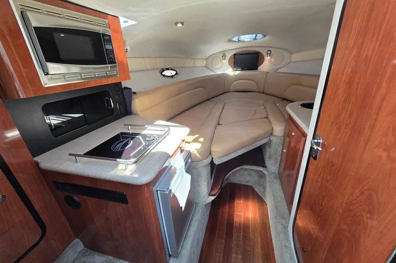 Slide: The Image of 2013 Crownline 325 SCR cabin interior with kitchenette and cozy seating area. - 13