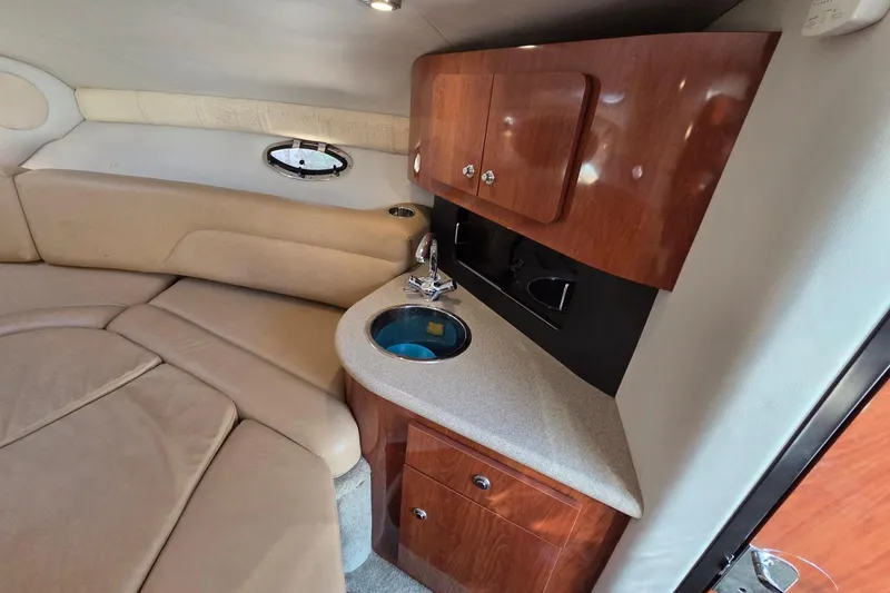 Slide: The Image of Interior of 2013 Crownline 325 SCR boat with beige seating and wooden cabinetry. - 15