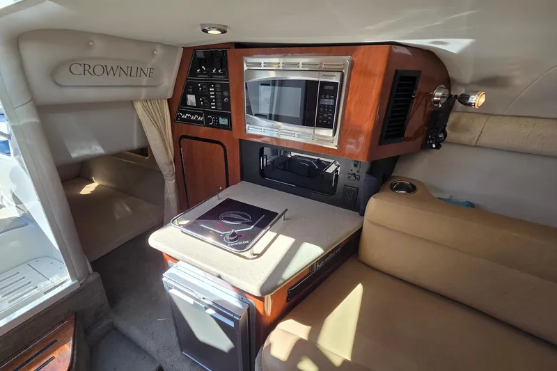 Slide: The Image of 2013 Crownline 325 SCR cabin interior with kitchenette, microwave, and seating area. - 17
