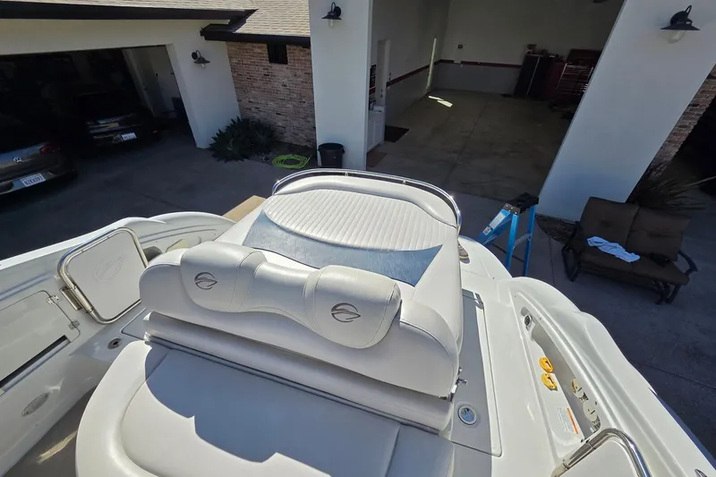 Slide: The Image of 2013 Crownline 325 SCR boat interior with white seating, parked near a garage. - 23