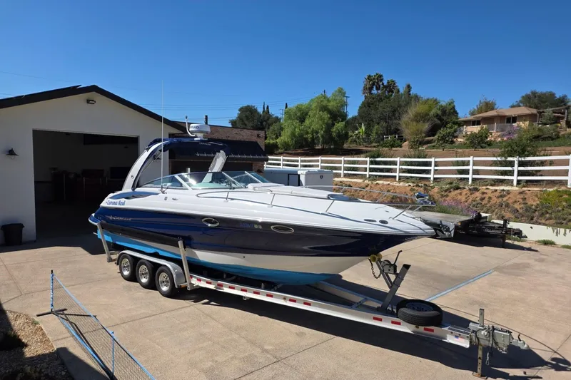 Slide: The Image of 2013 Crownline 325 SCR boat on trailer in driveway, sunny day, residential area. - 30
