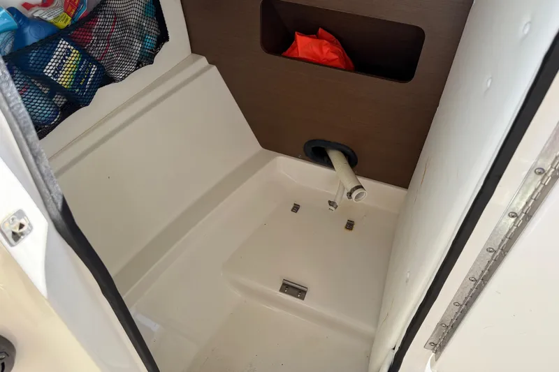 Slide: The Image of 2014 Sea Ray 240 Sundeck Outboard storage compartment with netted organizer and hose. - 22