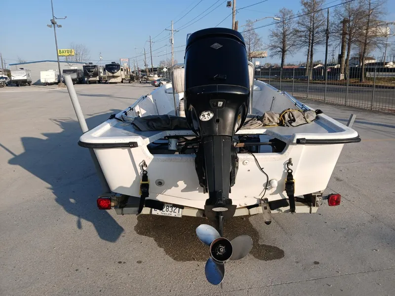 Slide: The Image of 2006 Kenner 21 boat on trailer with outboard motor, parked outdoors. - 4