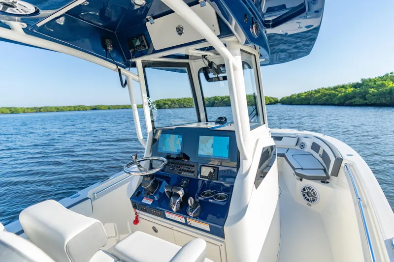 Slide: The Image of 2026 Cobia 245 Center Console boat interior with navigation screens, steering wheel, and seating on a sunny day. - 8