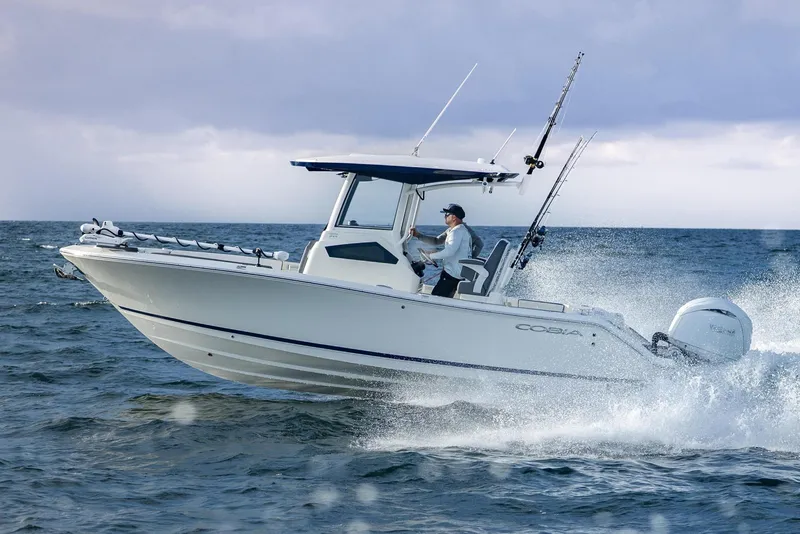 The Image of 2026 Cobia 245 Center Console boat navigating ocean waves under cloudy sky. - 0
