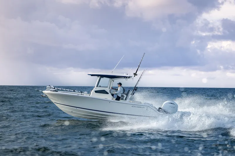 Slide: The Image of 2026 Cobia 245 Center Console boat cruising on open water, equipped for fishing. - 1