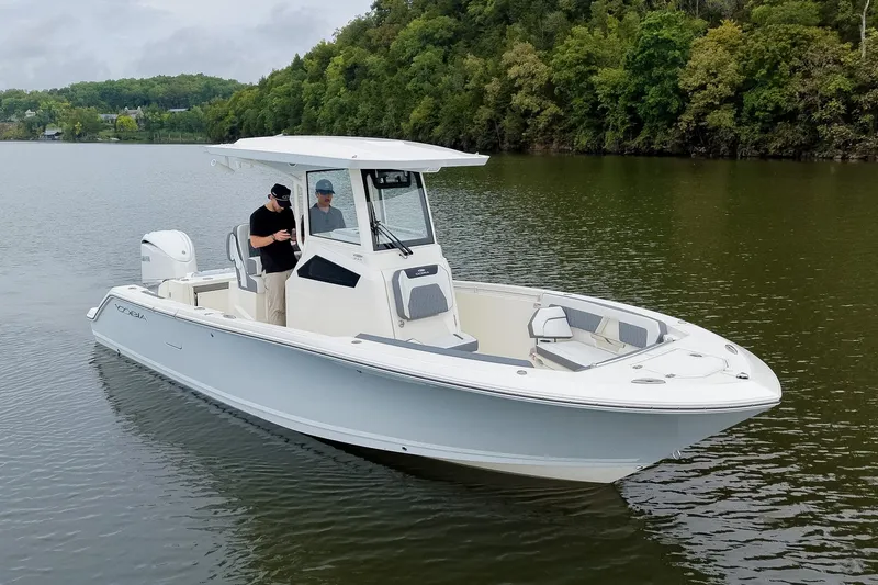 Slide: The Image of 2027 Cobia 245 Center Console boat on a calm lake with lush green shoreline. - 36