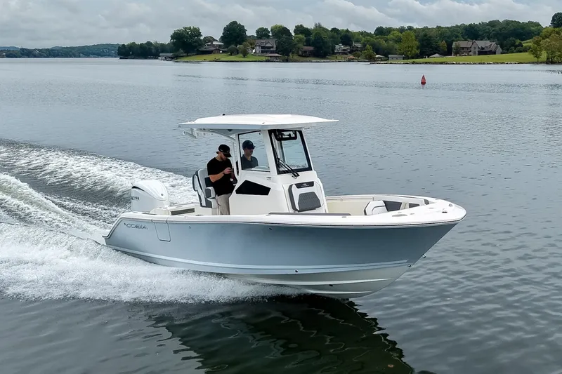 Slide: The Image of 2027 Cobia 245 Center Console boat cruising on a serene lake. - 27