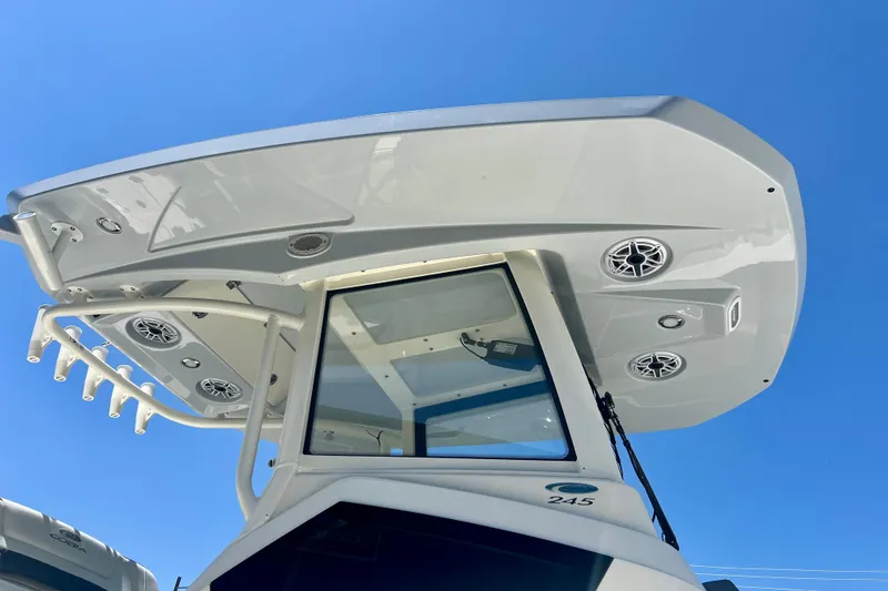 Slide: The Image of 2027 Cobia 245 Center Console boat with speakers, viewed from below against blue sky. - 19