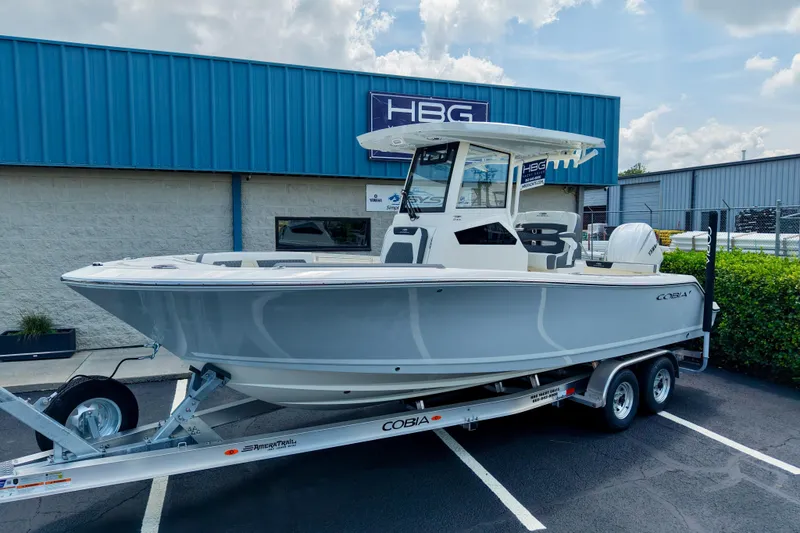 The Image of 2027 Cobia 245 Center Console boat on trailer, parked outside dealership. - 0