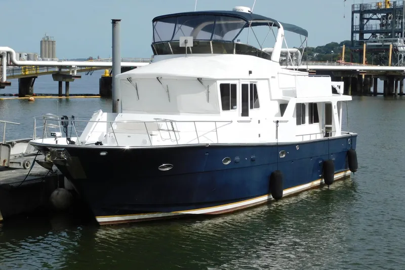 Slide: The Image of 2001 Jefferson Pilothouse 57 yacht docked at a marina, featuring a sleek blue and white design. - 2