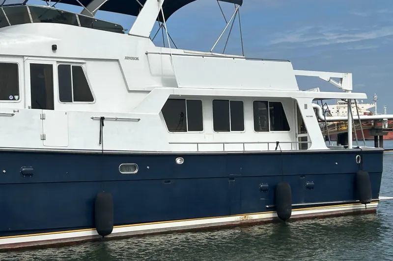 Slide: The Image of 2001 Jefferson Pilothouse 57 yacht docked, featuring a sleek blue and white design. - 4