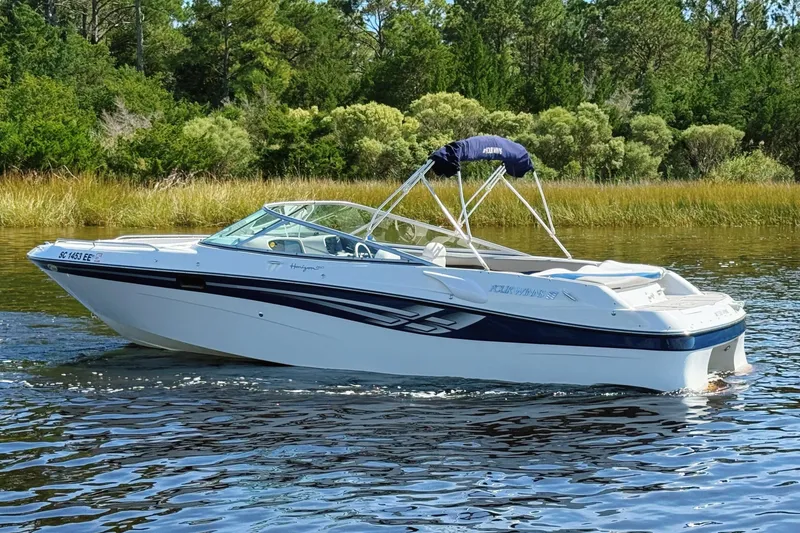 Slide: The Image of 2000 Four Winns 260 Horizon boat cruising on a calm lake with lush greenery. - 0