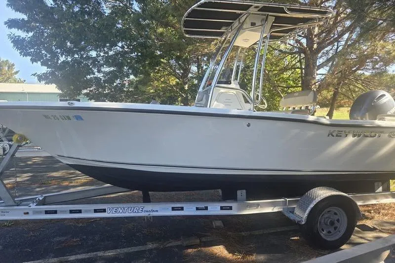 Slide: The Image of 2023 Key West 203 FS boat on trailer, parked outdoors under trees. - 10