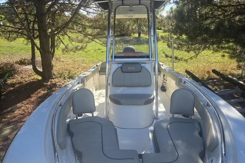 Slide: The Image of 2023 Key West 203 FS boat interior with seating and console, surrounded by trees. - 11