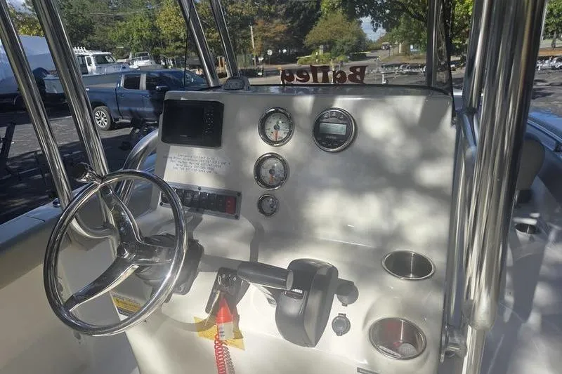 Slide: The Image of 2023 Key West 203 FS boat dashboard with steering wheel and gauges in a parking lot. - 16