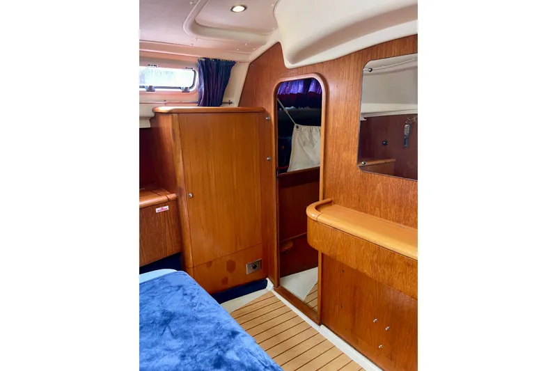 Slide: The Image of Interior of 2000 Moody 42 CC yacht with wooden cabinetry and blue bedding. - 16