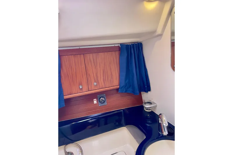 Slide: The Image of Interior of 2000 Moody 42 CC yacht bathroom with wooden cabinets and blue curtains. - 19