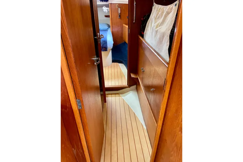 Slide: The Image of Narrow wooden hallway inside 2000 Moody 42 CC yacht, featuring storage and cozy cabin view. - 43