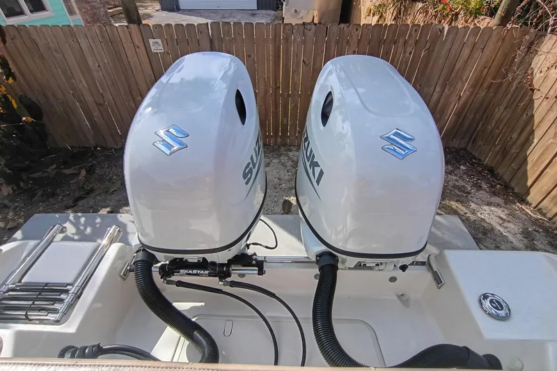 Slide: The Image of Twin Suzuki outboard engines on 2024 Sea Chaser 24 HFC boat, wooden fence background. - 18