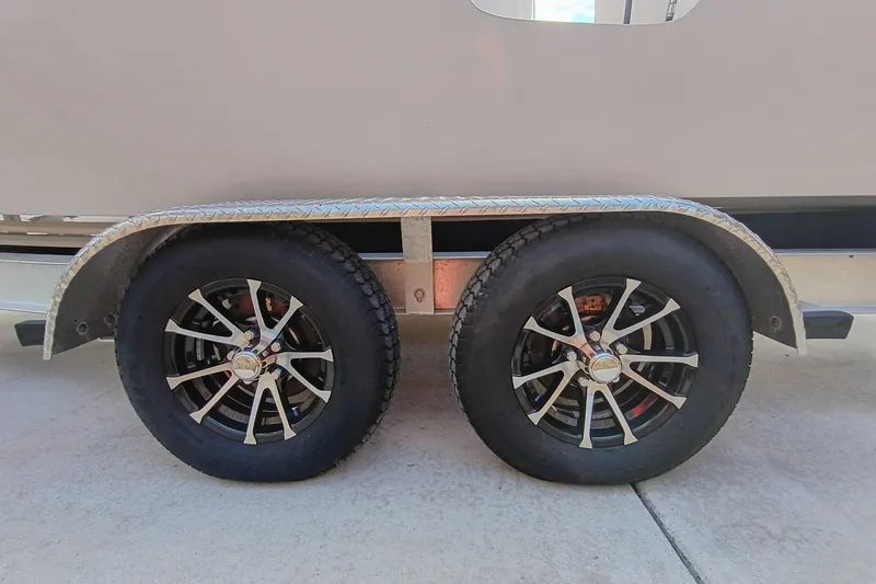 Slide: The Image of Trailer wheels of a 2024 Sea Chaser 24 HFC boat on concrete surface. - 19