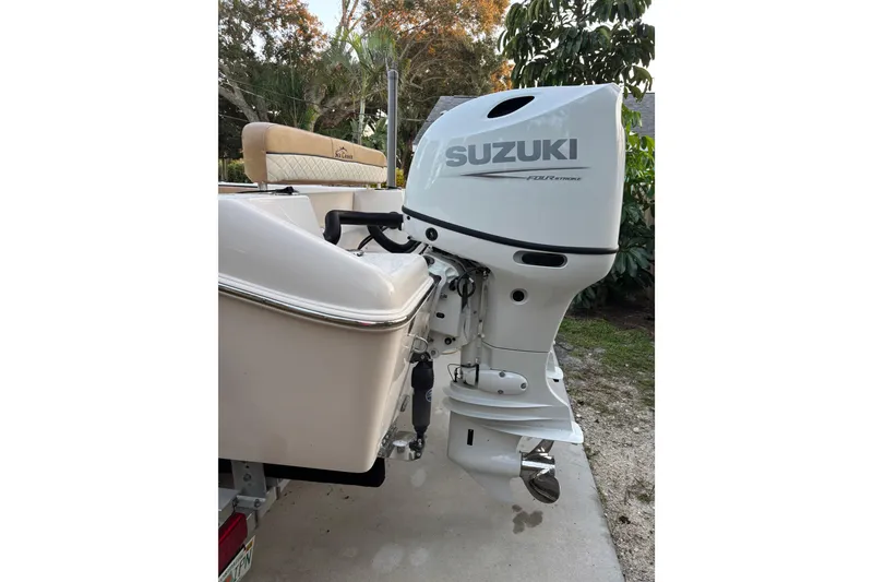 Slide: The Image of 2024 Sea Chaser 24 HFC boat on trailer in driveway, surrounded by trees and house. - 2