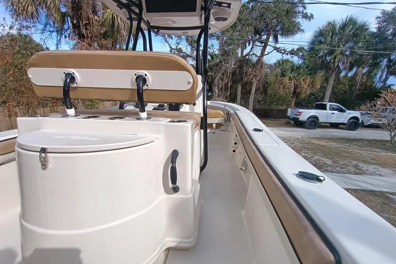 Slide: The Image of 2024 Sea Chaser 24 HFC boat interior with seating and storage, parked near trees and a truck. - 34