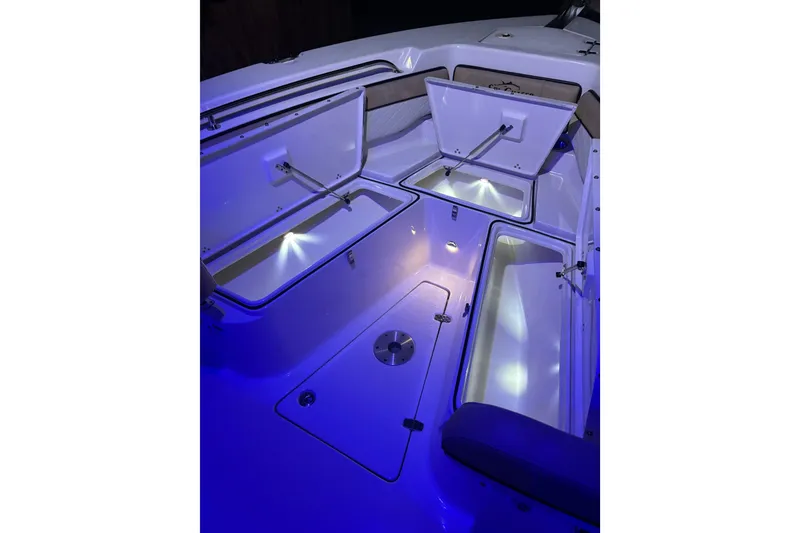 Slide: The Image of 2024 Sea Chaser 24 HFC boat illuminated with blue lights at night. - 73
