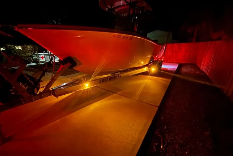 Slide: The Image of 2024 Sea Chaser 24 HFC boat on trailer, illuminated at night with red and yellow lights. - 80