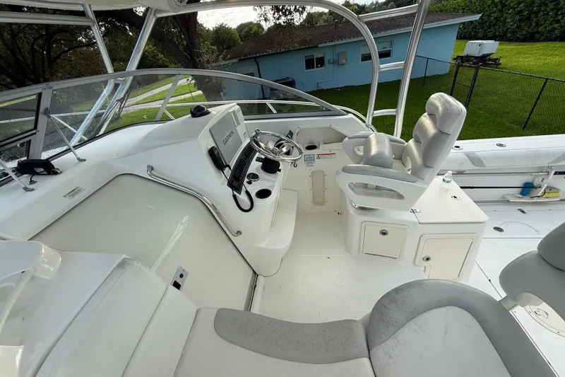 Slide: The Image of 2011 Boston Whaler 285 Conquest interior with white seating and helm, under sunny skies. - 17