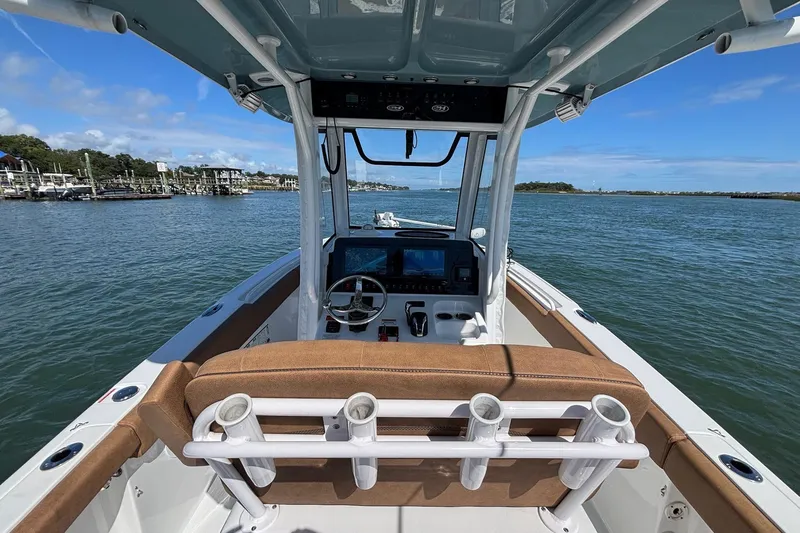 Slide: The Image of 2022 Sea Hunt Ultra 255 SE boat interior with helm, rod holders, and scenic water view. - 13