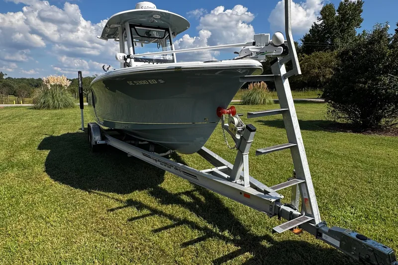 Slide: The Image of 2022 Sea Hunt Ultra 255 SE boat cruising on a calm lake with trees in the background. - 4