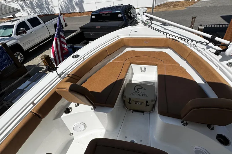Slide: The Image of 2022 Sea Hunt Ultra 255 SE boat with brown seating, cruising on a scenic waterway. - 8