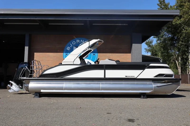 Slide: The Image of 2026 Harris Grand Mariner 250 pontoon boat parked outside a building. - 2