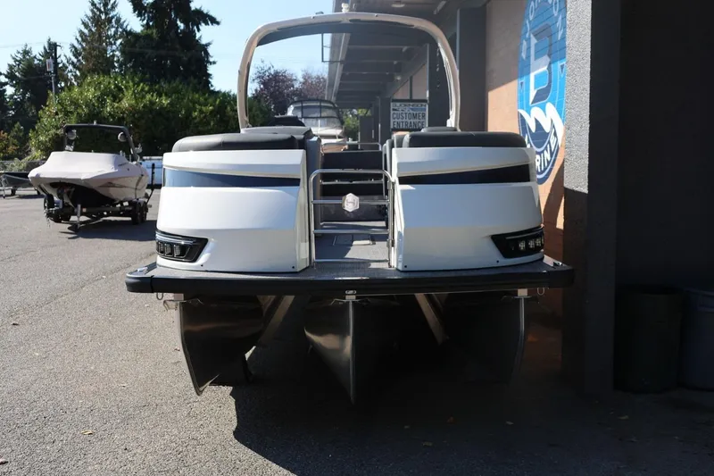 Slide: The Image of 2026 Harris Grand Mariner 250 pontoon boat, rear view, parked outdoors near a building. - 5