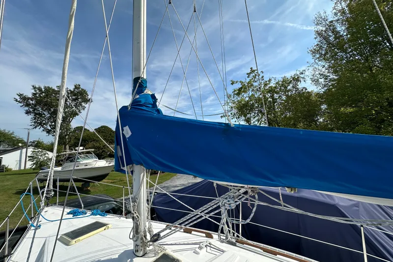 Slide: The Image of 1985 Hunter 28.5 sailboat with blue sail cover, docked on grassy area. - 7
