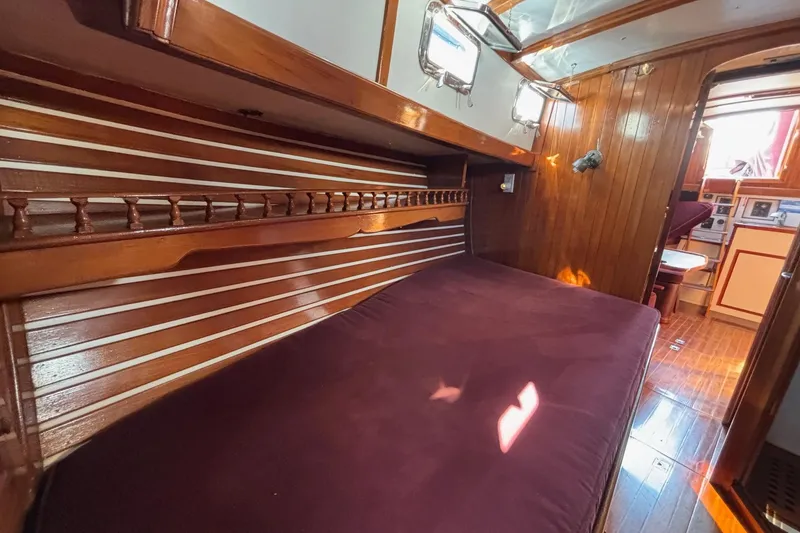 Slide: The Image of Cozy 1978 Tayana Mariner cabin interior with wooden paneling and plush bedding. - 14