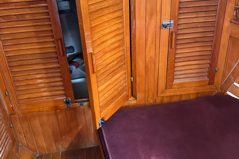 Slide: The Image of 1978 Tayana Mariner interior with wooden cabinets and purple cushioned seating. - 15