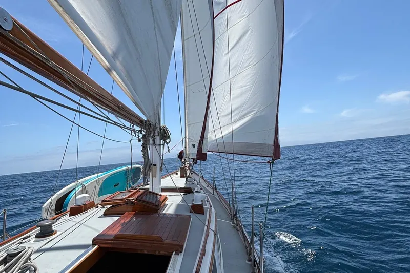 Slide: The Image of 1978 Tayana Mariner sailboat navigating open sea under clear blue skies. - 2