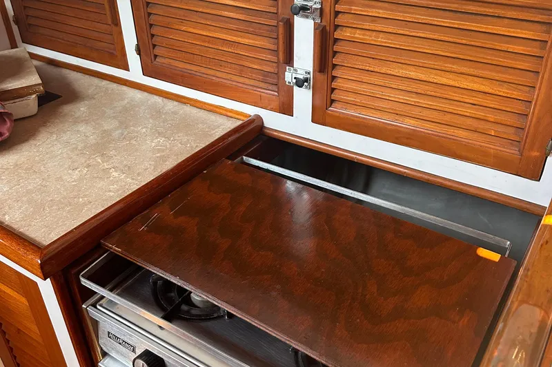 Slide: The Image of 1978 Tayana Mariner yacht kitchen with wooden cabinets and stove. - 28