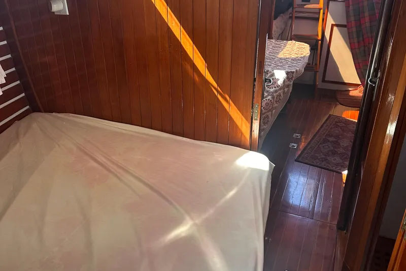 Slide: The Image of Cozy wooden interior of a 1978 Tayana Mariner sailboat with beds and warm lighting. - 32