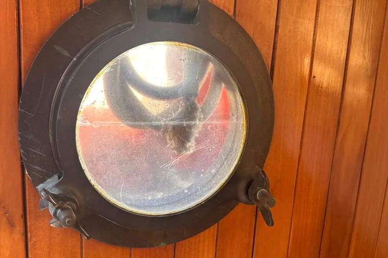 Slide: The Image of Round porthole on 1978 Tayana Mariner, set in wooden paneling. - 37