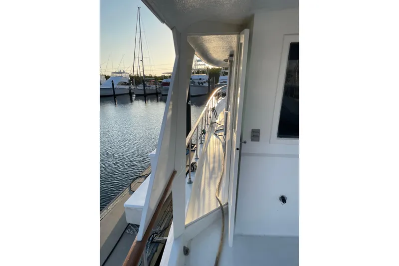 Slide: The Image of 1973 Hatteras 58 Yacht Fisherman docked, showcasing side deck and marina view. - 13