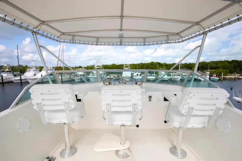 Slide: The Image of 1973 Hatteras 58 Yacht Fisherman helm with white seating and marina view. - 19