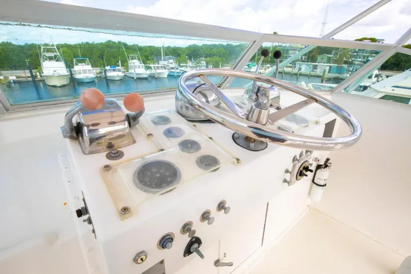 Slide: The Image of 1973 Hatteras 58 Yacht Fisherman helm with steering wheel and controls, docked at marina. - 20