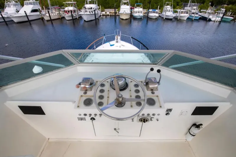 Slide: The Image of 1973 Hatteras 58 Yacht Fisherman helm with steering wheel, controls, and marina view. - 22