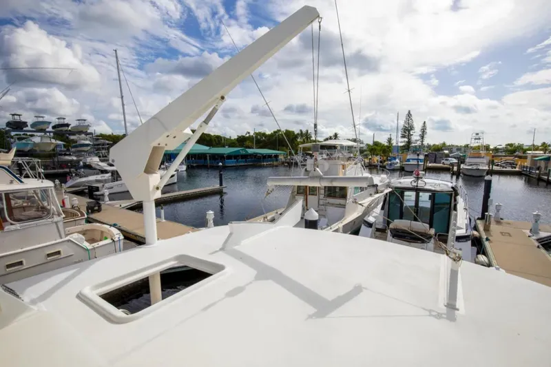 Slide: The Image of 1973 Hatteras 58 Yacht Fisherman docked at a marina under a partly cloudy sky. - 24