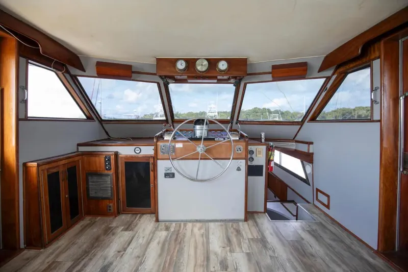 Slide: The Image of 1973 Hatteras 58 Yacht Fisherman helm with wooden accents and panoramic windows. - 35