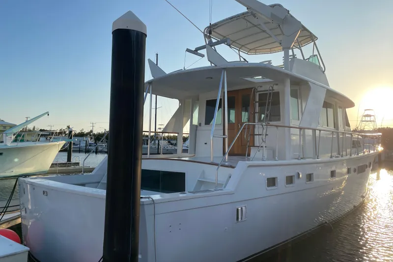 Slide: The Image of 1973 Hatteras 58 Yacht Fisherman docked at sunset, showcasing elegant design and spacious deck. - 4